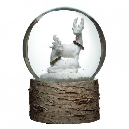 A large snow globe with a natural bark base and snowy winter reindeer scene.