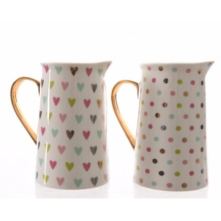 An assortment of 2 pretty multi-coloured heart and polka dot design jugs, each with a gold handle.