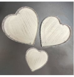 A set of 3 metal heart shaped trays each with a decorative pattern.
