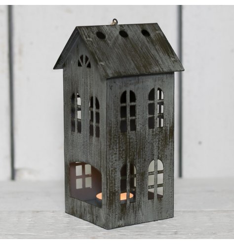 A charcoal grey distressed metal T-light holder in the shape of a house with heart cut out.