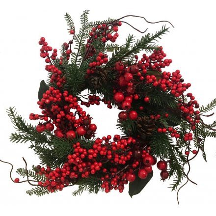  A decorative wreath built up with pine and fern foliage, topped with a light scatter of festive red berries