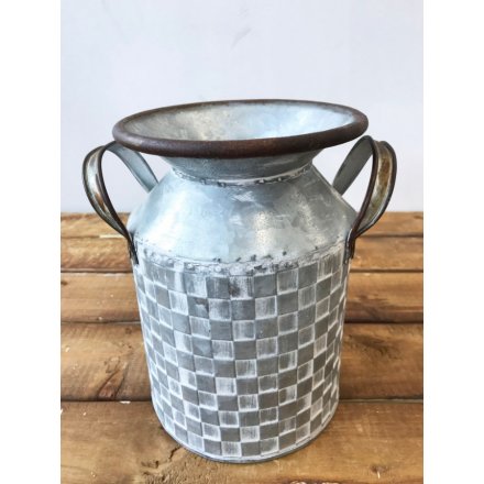 A charming zinc metal churn with a decorative patchwork tile pattern and twin handles.
