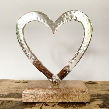 A stylish and chic large aluminium open heart decoration on a mango wooden base for interior display.