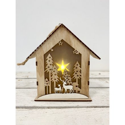A natural toned wooden house decoration complete with a cut out woodland scene and warm glowing LED surround
