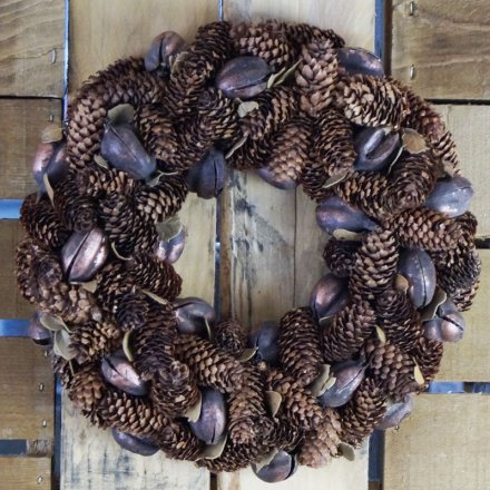 A beautifully decorated round wreath decorated with a cluster of sized pinecones and shells 