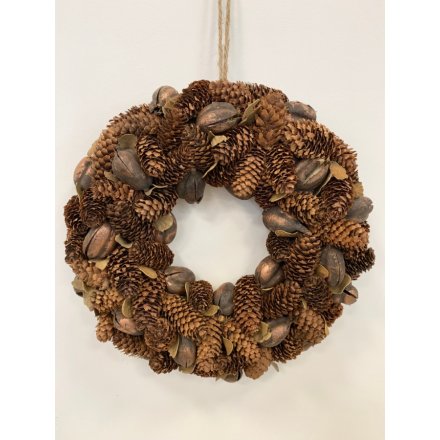 A beautifully decorated round wreath covered with a cluster of sized pinecones and shells 