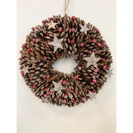 A large round oasis built up of chunky frosted pinecones, covered with a flurry of stars and red berries 