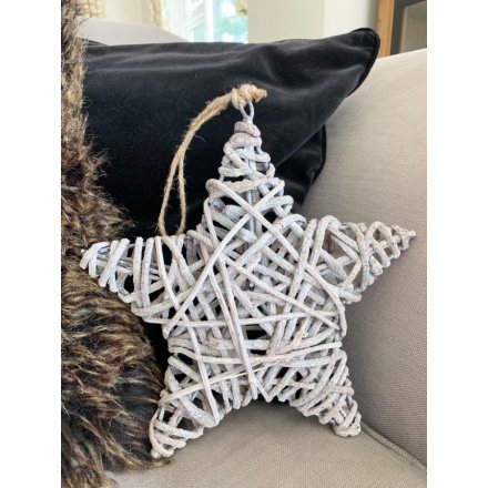   A large hanging grey toned star made up of rustic woven rattan and hung from a jute string 