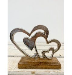 A rustic aluminium double heart decoration set upon a chunky wooden block.