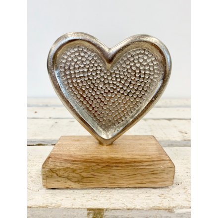 A chic silver heart ornament with a dotty decorative pattern and natural wooden base.