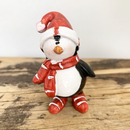 Adorable penguin figures wearing red and white striped boots and scarves, complete with Santa hats.