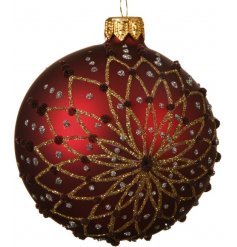 A decorative glass bauble with a matt base and glitter flower decoration.