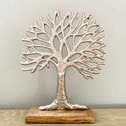 A rough luxe silver tree of life ornament set upon a chunky wooden base. 