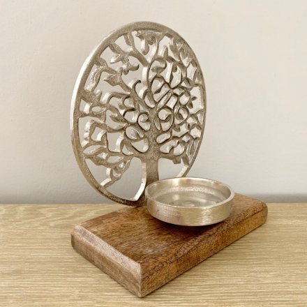 A chic candle holder featuring a rustic metal tree of life figure enclosed within a circle. 