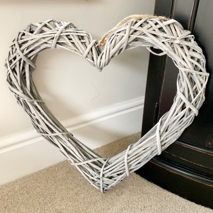A large rustic rattan heart shaped wreath with woven branches and a chunky rope hanger.