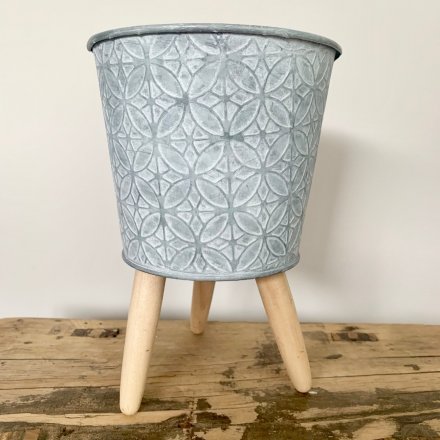 this zinc metal planter is rested upon 3 natural wooden legs and also displays a rustic charm finish 