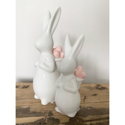 A chic bunny ornament with a basket full of pink eggs.