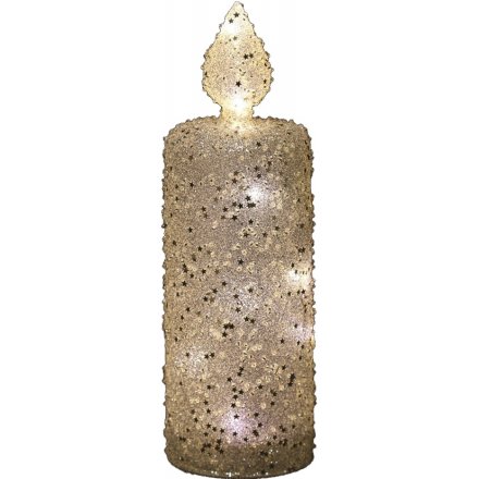 A tall LED Candle covered in glittery stars and sequins 