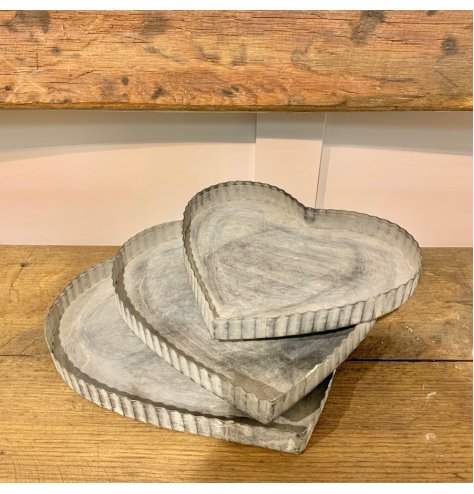 An assorted sized set of heart shaped metal trays with a ridged edge 