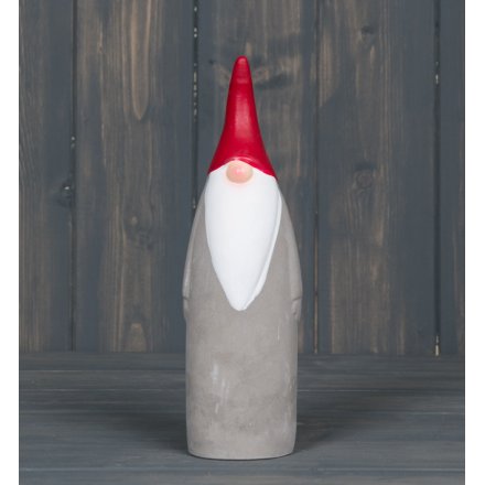 A tall standing concrete Gnome with a pointed red hat 