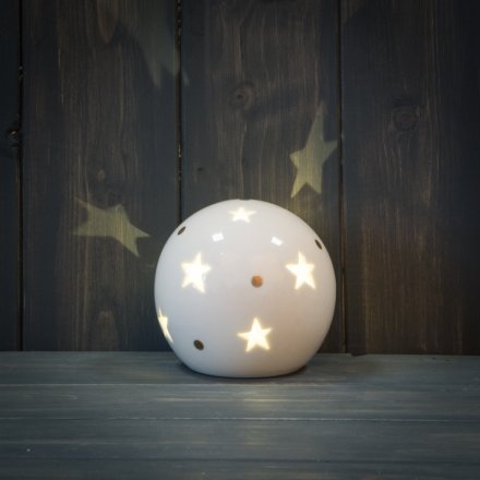 A smooth ceramic ball ornament with a star cut decal and warm glowing LED centre 
