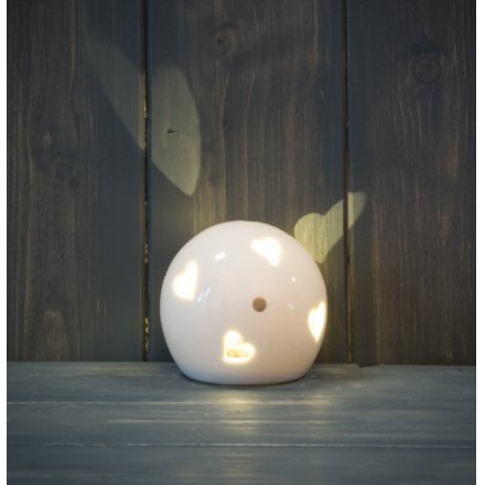A smooth ceramic ball ornament with a heart cut decal and warm glowing LED centre 