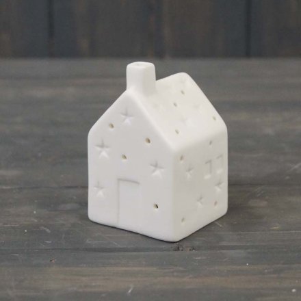 A small white ceramic house decoration with a warm glowing LED centre 