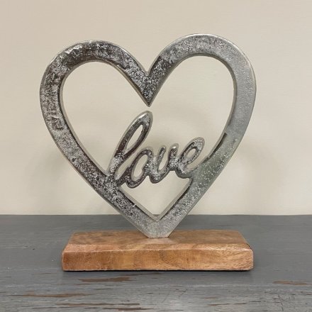  Set with a natural wooden block base, this decorative aluminium heart also features a scripted text centre 