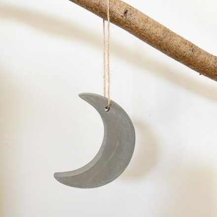 A rustic cement moon decoration with a jute string hanger.