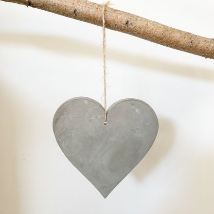 A rustic cement heart decoration with a jute string hanger.