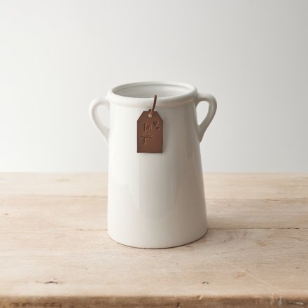 A classic white ceramic vase with small eared handles. A timeless home accessory, complete with a stylish tag.