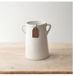 A classic white ceramic vase with small eared handles. A timeless home accessory, complete with a stylish tag.