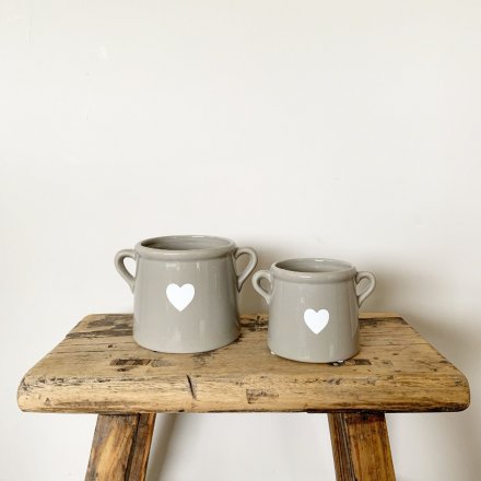 A beautiful ceramic pot with a chic white heart decal. Complete with small handles.