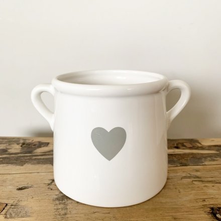 A classic white ceramic pot with a grey heart detail. Complete with twin handles. 