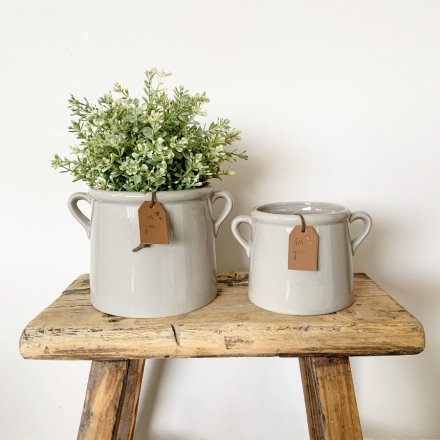 A stylish grey ceramic pot planter with small eared handles. Complete with a tan coloured PU leather slogan tag.