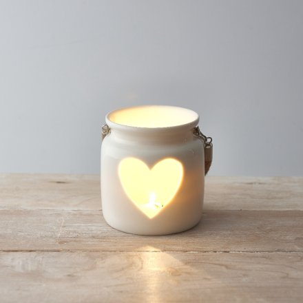 A rustic ceramic lantern with a white finish. Complete with a heart cut out design and chunky rope handle.