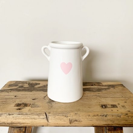 A pretty vase with small handles and a pink heart shaped design.