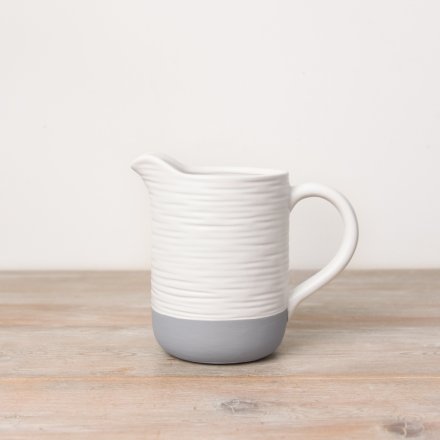 A rustic white and grey jug with a ribbed surface texture, creating a unique handmade feel.