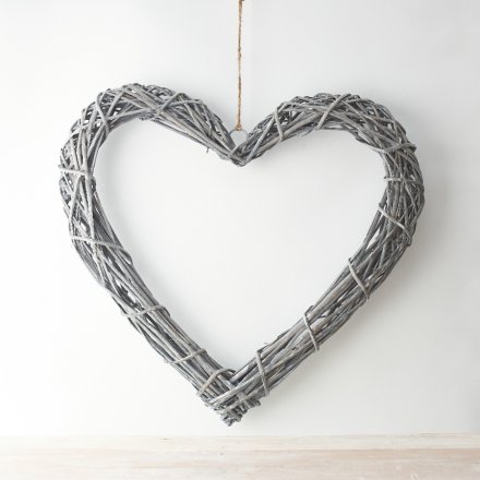 A rustic rattan heart wreath with a woven design and chunky jute rope hanger.