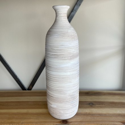 A tall standing ribbed vase with a neutral colour tone and a rustic finish 