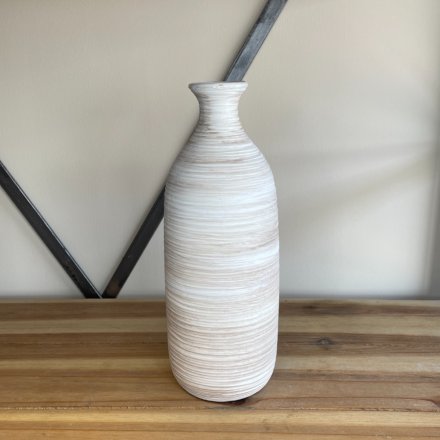 A tall standing ribbed vase with a neutral colour tone and a rustic finish 