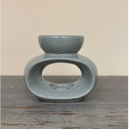 A small ceramic oval shaped tlight holder with an added wax and oil dip dish 