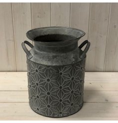A gorgeously tarnished metal churn, featuring an embossed geometric daisy decl around it 