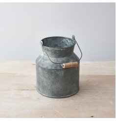 a small decorative metal churn with an overly distressed setting and wooden handle to finish 