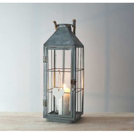a tall standing metal lantern with a white washed finish and chunky rope handle
