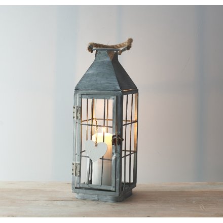 a tall standing metal lantern with a white washed finish and chunky rope handle
