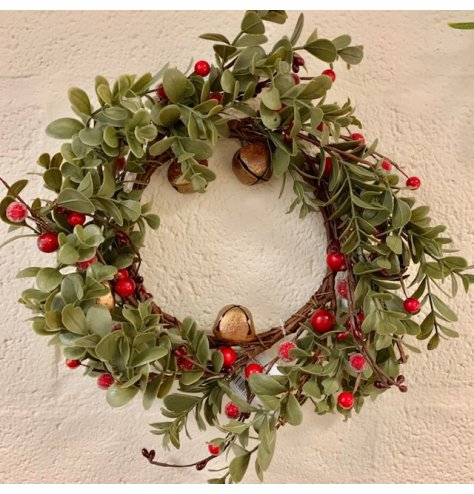 A large and full green foliage wreath set with added red berries and glitter gold bells 