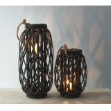A dark toned woven wicker lantern with a chunky rope handle accent and glass insert 