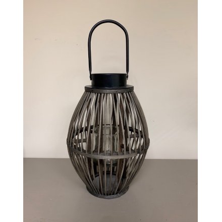 A contemporary inspired wooden lantern featuring a rustic grey toned finish and metal handle 
