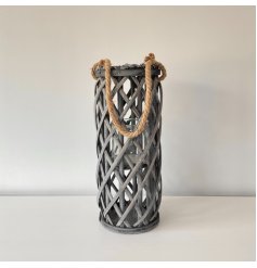 a tall standing wooden lantern with a lattice pattern and chunky rope handle 